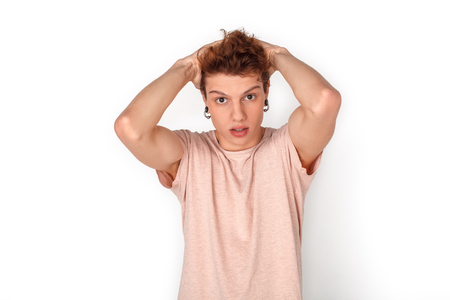 Teenager with earrings studio standing isolated on white holding head concerned close-upの写真素材