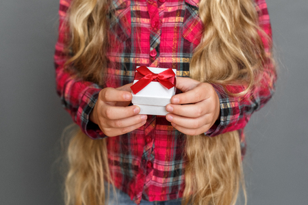 Little girl standing isolated on grey with gift box close-upの写真素材