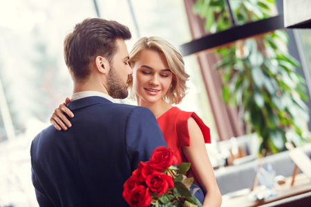 Young couple on date in restaurant dancing sensual holding bouquetの写真素材