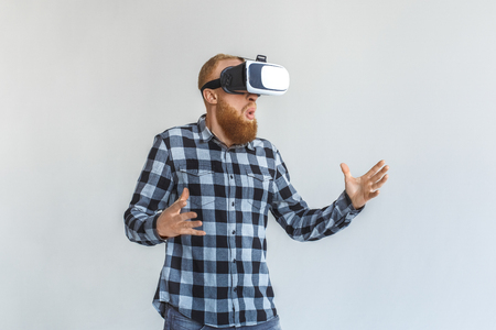Freestyle. Mature man in virtual reality headset standing isolated on grey playing excitedの写真素材