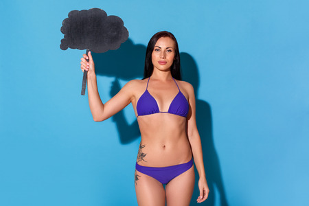 Freestyle. Woman in bikini standing isolated on blue wall with speech bubble confidentの写真素材