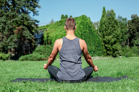 Healthy Lifestyle. Man practicing yoga outdoors sitting back doing meditation calmの写真素材
