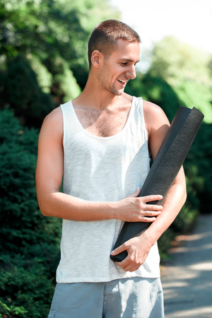 Healthy Lifestyle. Man practicing yoga outdoors standing looking at mat cheerfulの写真素材