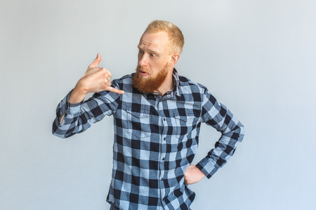Freestyle. Mature man standing isolated on grey showing call gesture confusedの写真素材
