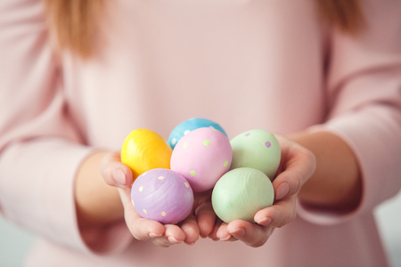 Young woman at home easter celbration concept in a bunny ears holding colorful eggs close-upの写真素材