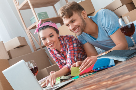 Young couple moving to new place lying drinking wine browsing internet searching for design ideas cheerfulの写真素材