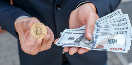 Money type. Businessman standing on the city street with coin and banknotes close-upの写真素材