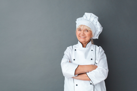 Senior woman chef studio standing isolated on gray crossed arms smiling confidentの写真素材