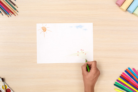 Wooden desk creative workplace top view person drawing picture with color pencilsの写真素材