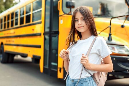 Kid with bag standing near bus going to school posing to camera pensive close-upの写真素材