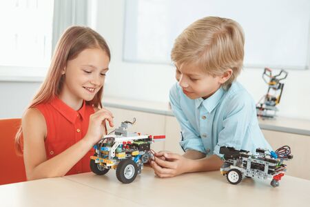 Robotics. Brother and sister having class sitting making robots cheerfulの写真素材