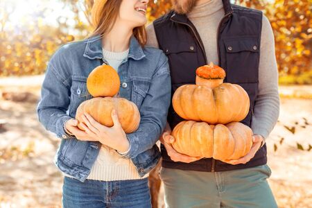 Halloween Preparaton Concept. Young couple standing at garden with pumpkins close-up looking at each other joyfulの写真素材