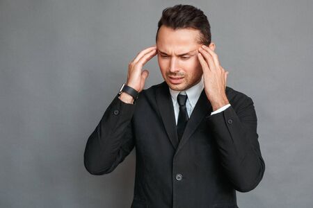 Businessman studio standing isolated on grey having headache touching head unhappy