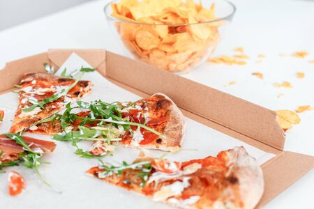 Fast food box of pizza and bowl of chips isolated on the kitchen table close-upの写真素材