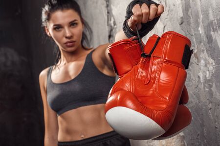 Boxing. Woman boxer showing gloves to camera close-up standing isolated on wall blurredの写真素材