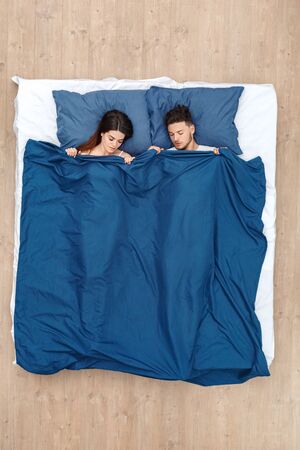 Bedtime. Young couple sleeping peaceful on bed under blanket top viewの写真素材