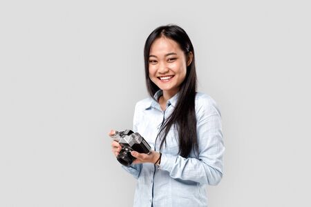 Freestyle. Asian girl photographer isolated on white holding camera laughing cheerfulの写真素材