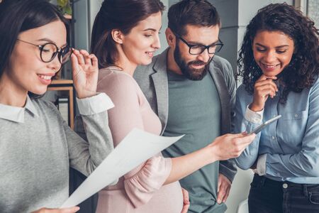 Startupers working together at office standing pregnant woman watching video on digital tablet smiling happy close-upの写真素材