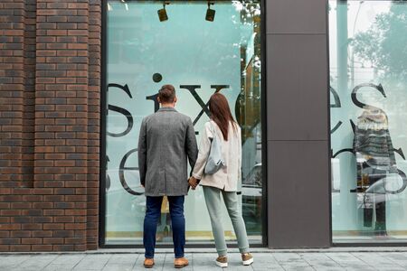 Adult woman and man looking at showcase in shopping mallの写真素材