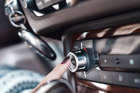 Electric car interior mode of transport woman pushing ac and ventilation control panel button close-upの写真素材