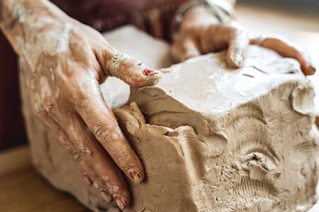 Young woman making pottery indoors craftsperson concept modeling piece of clay dirty hands close-upの写真素材