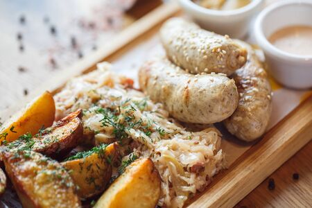Lunch Time. Sausages potatoes and braised cabbage on board isolated on table close-upの写真素材