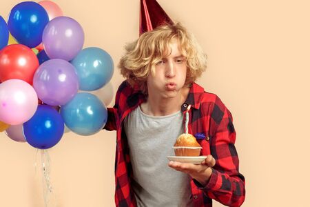 Young adult guy blowing on candle at birthday cupcake