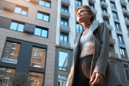 Urban Style. Young stylish woman in coat standing outdoors breathing relaxed bottom viewの写真素材