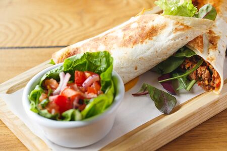 Lunch Time. Burrito and salad isolated on table close-upの写真素材