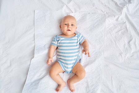 Little new born baby looking at camera, lying on bedの写真素材