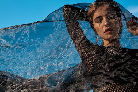 Urban Style. Young stylish woman standing outdoors under veil posing sensual