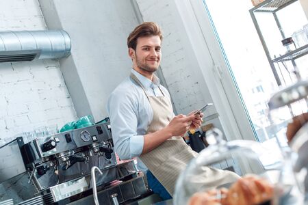 Young adult barista working in restaurant, using modern tabletの写真素材