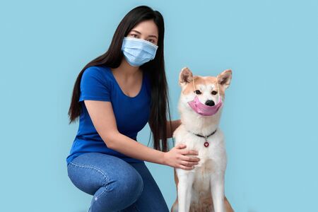 Young adult asian girl and her dog wearing in safety maskの写真素材