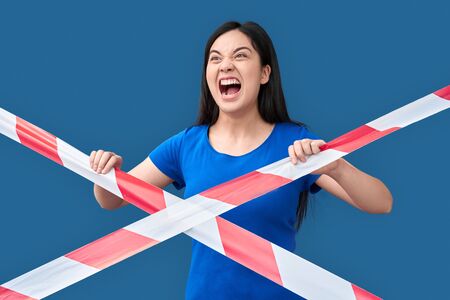 Young adult asian girl screaming, standing behind caution line