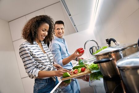 Young adult man and afro american woman cooking dinner at homeの写真素材
