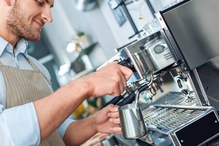Young adult barista working in cafe, whipping milk for coffeeの写真素材