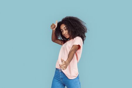 Freestyle. African girl standing isolated on gray posing thumbs up smiling coolの写真素材