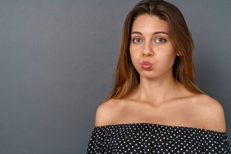 Young woman casual studio isolated on gray pouting lipsの写真素材