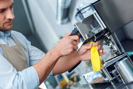 Coffee Passion. Young barista at coffee shop cleaning steamer concentrated close-upの写真素材