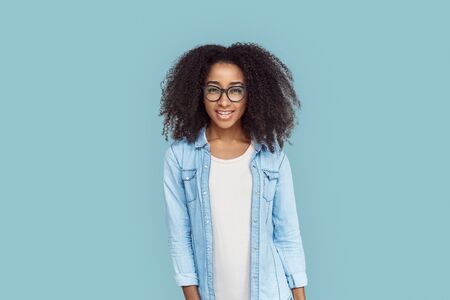 Freestyle. African girl in glasses standing isolated on gray looking camera doubtfulの写真素材