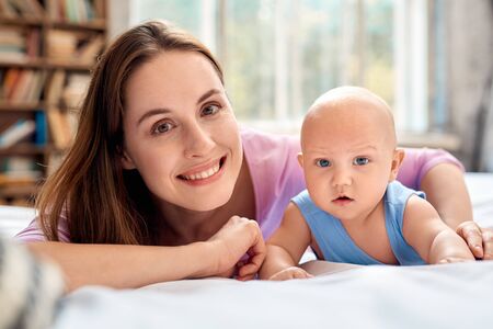 Young adult mom and little new born baby lying on bedの写真素材