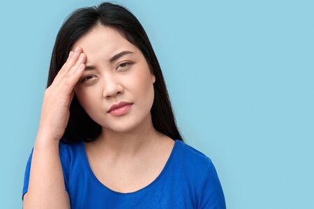 Young adult asian woman with headache standing against grey backgroundの写真素材