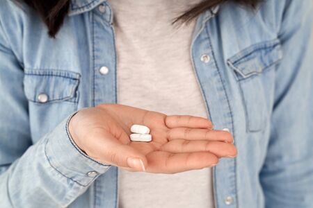 Coronavirus Concept. Chinese woman in jean jacket standing isolated on greyholding pills close-upの写真素材