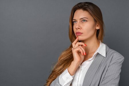 Young business woman studio isolated on gray thoughtful close-up