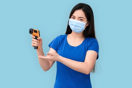 Young adult asian woman showing infrared thermometer in handの写真素材