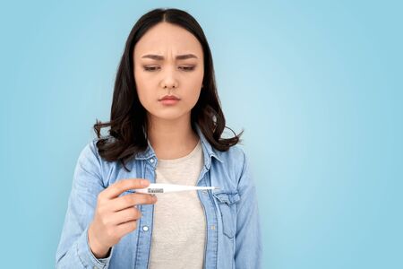 Young adult asian woman checking temperature with thermometer