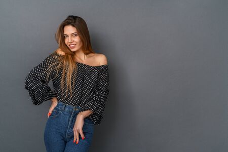 Young woman casual studio isolated on gray posing looking camera shyの写真素材
