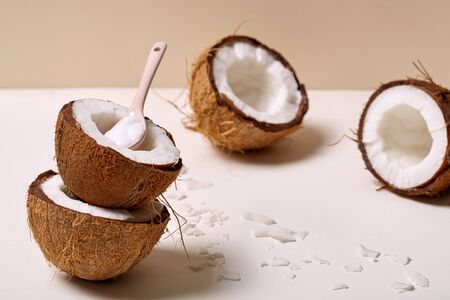 Halved organic coconuts isolated on nude background with spoon full of body cream close-upの写真素材