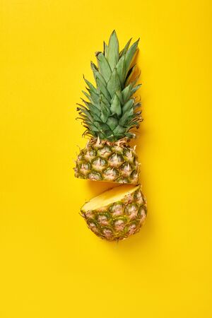 Halved pineapple isolated on yellow background healthy eatingの写真素材