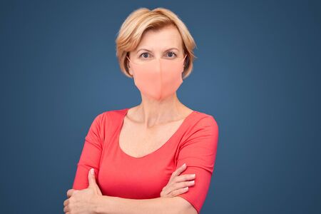 Mature woman in protective face mask looking at cameraの写真素材
